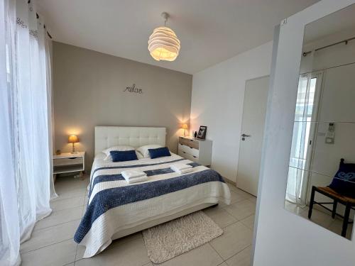 une chambre blanche avec un grand lit avec des oreillers bleus dans l'établissement Appartement Rivages 100m plage CALVI, à Calvi