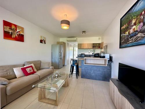 un salon avec un canapé et une cuisine dans l'établissement Appartement Rivages 100m plage CALVI, à Calvi