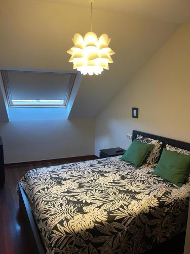 a bedroom with a bed with green pillows and a chandelier at Apartamento Portela in Bueu