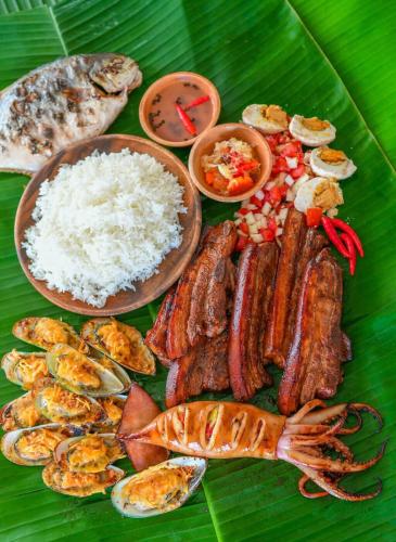 a plate of food with rice and meats on a banana leaf at On-the-beach JADE's BEACH VILLA 별장 Lapu-lapu Olango 별장 in Lapu Lapu City