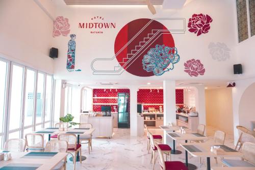 a restaurant with tables and chairs and a sign on the wall at Hotel Midtown Ratsada in Phuket Town