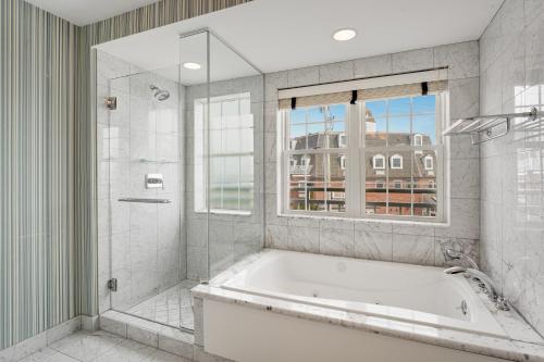 baño con bañera y ducha y ventana en Newport Beach Hotel & Suites, en Middletown