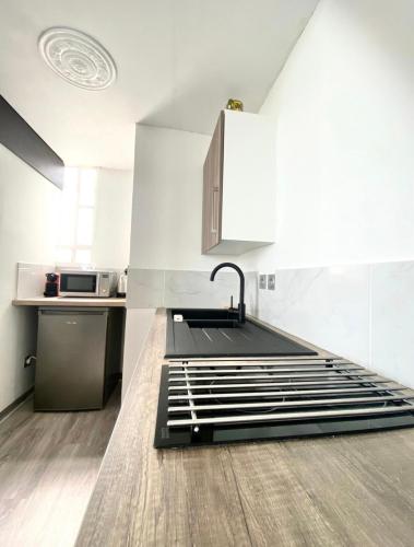 - une cuisine aux murs blancs avec un évier et un comptoir dans l'établissement Appartement Cosy, au Cannet