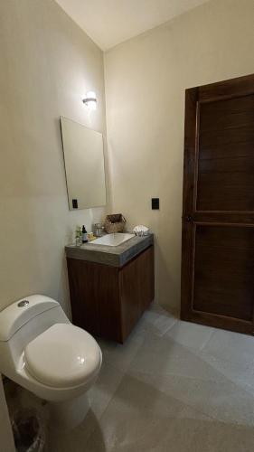 a bathroom with a toilet and a sink and a mirror at Hotel Casa Barbara Holbox in Holbox Island