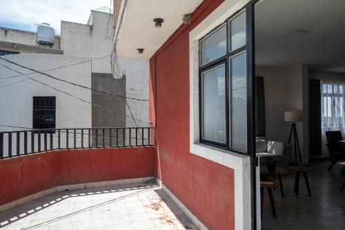 a room with a red wall and a window at Departamento Blomi in San Juan de los Lagos