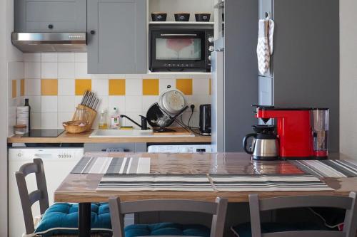 une cuisine avec une table en bois et un appareil rouge dans l'établissement Appt lumineux, Thermes et Montagne, à La Bourboule
