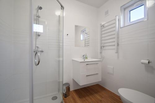 a white bathroom with a shower and a sink at Westbeach House in Grzybowo