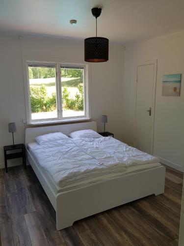 a white bed in a bedroom with two windows at Landhaus Lönneberga in Lönneberga