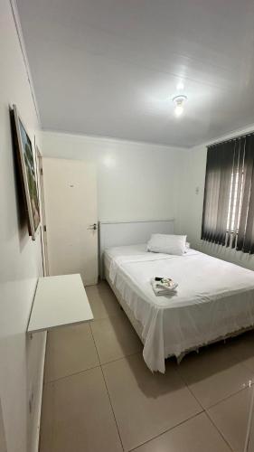 a bedroom with a white bed and a window at Hotel Rota Dos Tropeiros in Castro