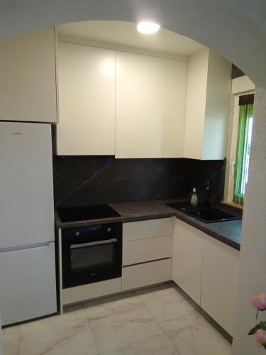 a kitchen with white cabinets and a black oven at Apartman Pavic in Pag