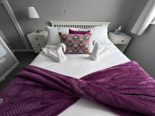 a bed with a purple blanket and two stuffed animals on it at Dog Friendly Beachside Cottage Kessingland with private parking in Kessingland