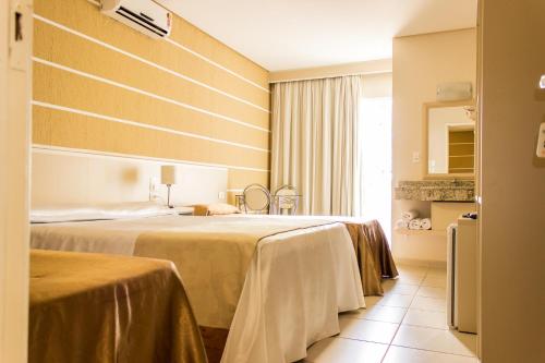 a hotel room with two beds and a window at Pousada Cataratas in Foz do Iguaçu