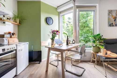 een keuken met een tafel en stoelen en een raam bij Cozy House - fietsverhuur, eigen keuken en badkamer in Nijmegen