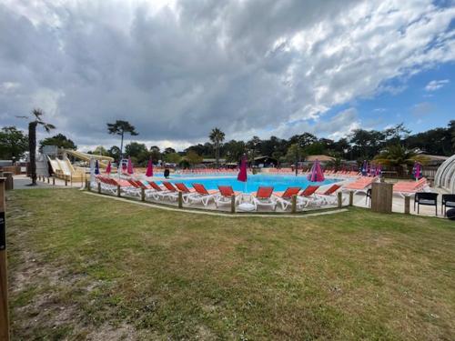 une grande piscine avec des chaises longues dans un parc dans l'établissement Mobilhome dans camping siblu les Viviers, à Lège-Cap-Ferret