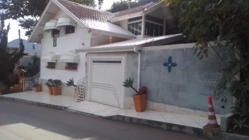 una casa blanca con una puerta y plantas delante de ella en MINHA CASA,SUA CASA en São Bento do Sapucaí