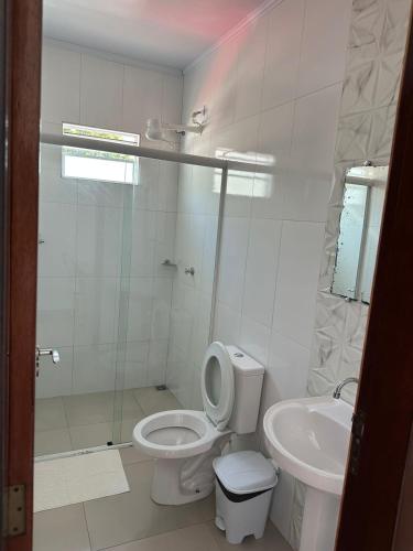 a white bathroom with a toilet and a sink at Hotel Rota Dos Tropeiros in Castro