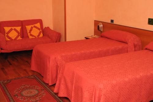 a hotel room with two beds and a chair at Hotel La Ruota in Pianfei