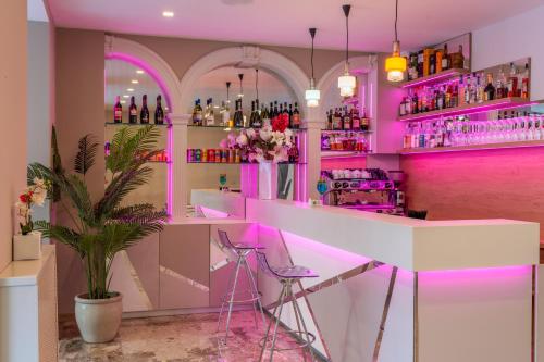 un bar con illuminazione rosa in una stanza con una pianta di HOTEL la SERENISSIMA TERME & SPA ad Abano Terme