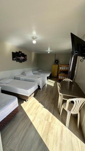 a room with several beds and a flat screen tv at Hotel Rota Dos Tropeiros in Castro