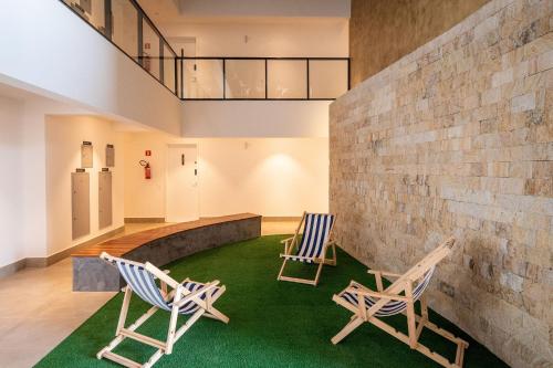 2 sillas sentadas en una habitación con alfombra verde en Lindos apto com piscina no Setor Oeste IDV, en Goiânia