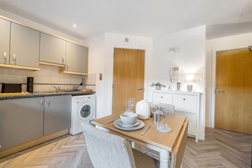 a kitchen with a wooden table and a kitchen with a dishwasher at Anchor in Basingstoke