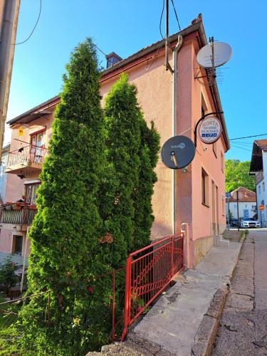 a building with two trees next to a red fence at Apartmani Konta in Livno