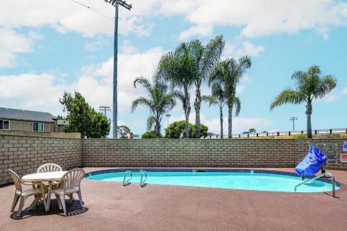 uma piscina com mesa e cadeiras ao lado de uma parede de tijolos em Hyland Inn near Legoland em Carlsbad