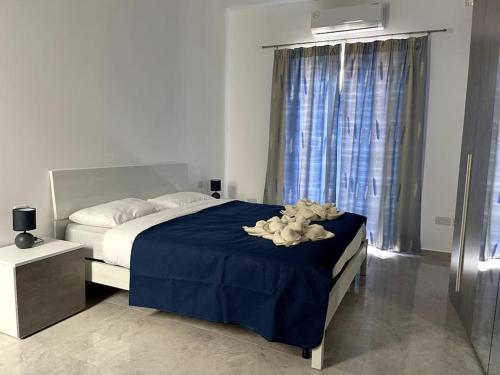1 dormitorio con 1 cama con manta azul y ventana en Apartment, Few Steps from Ghadira Bay, en Mellieħa