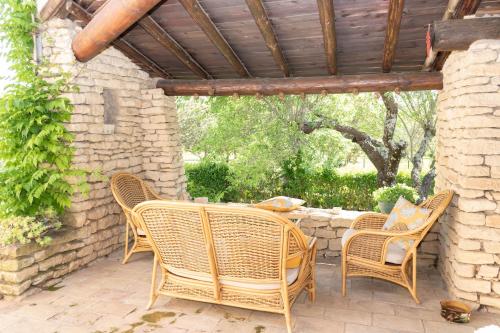 un patio al aire libre con sillas de mimbre y una mesa en VILLA PROVENCALE FACE AU LUBERON, en Cabrières-dʼAvignon
