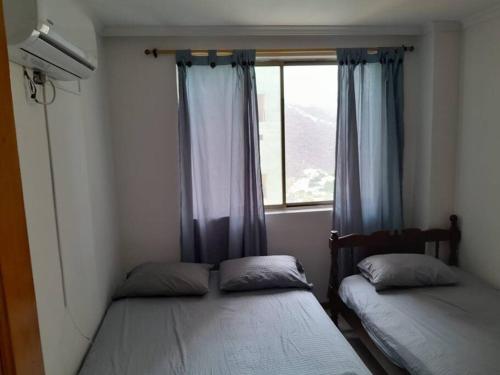 2 camas en una habitación pequeña con ventana en Alojamiento en Santa Marta, en Santa Marta