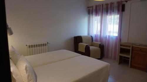 a bedroom with two beds and a chair and a window at Apartamentos na Quinta Altavista do Carvalhal in Zambujeira do Mar