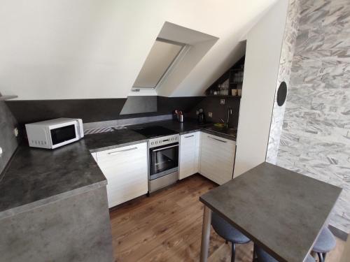 a small kitchen with white cabinets and a microwave at Apartmán Čeložnice in Čeložnice