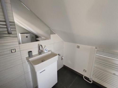 a white bathroom with a sink and a mirror at Apartmán Čeložnice in Čeložnice