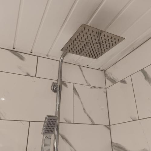a shower head in a bathroom with white tiles at City Hideaway in Leeds in Leeds
