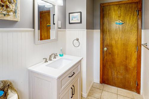 a bathroom with a sink and a wooden door at Spirit of the Sea in Mashpee