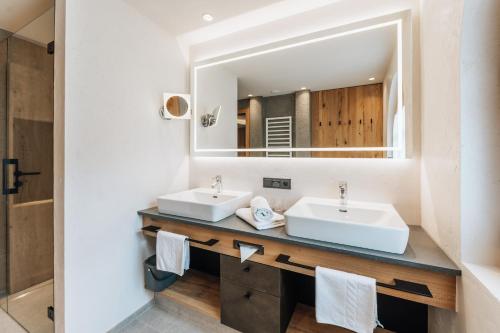 a bathroom with two sinks and a mirror at Vital Sporthotel Kristall in Finkenberg