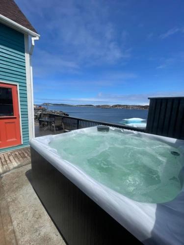 a hot tub on a deck with a view of the water at Jagged Rocks in Twillingate