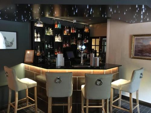 - un bar avec trois chaises et un comptoir avec des bouteilles dans l'établissement OYO Auldgirth Inn, à Auldgirth