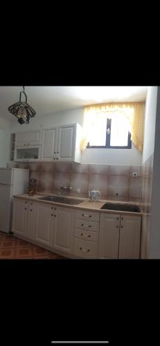 a white kitchen with a sink and a window at Pipo apartmentS in Ulcinj