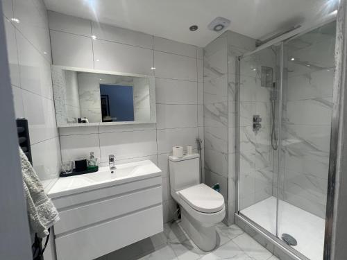 een witte badkamer met een toilet en een douche bij Clapham Oasis: Relax & Explore! in Londen