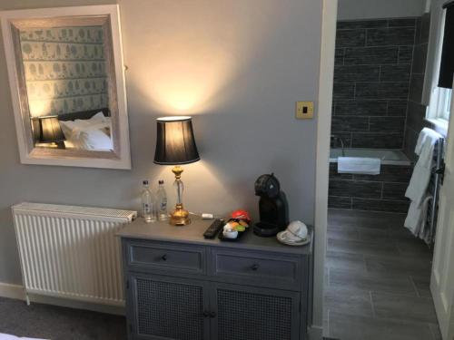een lamp op een dressoir in een badkamer met een bad bij OYO Auldgirth Inn in Auldgirth