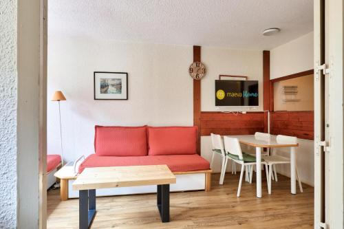 un salon avec un canapé rouge et une table dans l'établissement L'Aiguille - maeva Home - 2 Pièces 5 Personnes Sélection MAE-1179, à Chamonix-Mont-Blanc