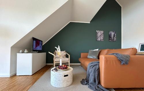ハノーファーにあるneues trendy Dachgeschossloftの緑の壁のリビングルーム(オレンジ色のソファ付)