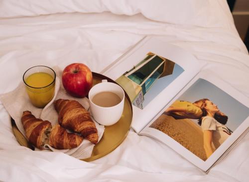 Un plato de desayuno con una manzana y una taza de café y un libro. en H La Paloma Boutique, en Barcelona