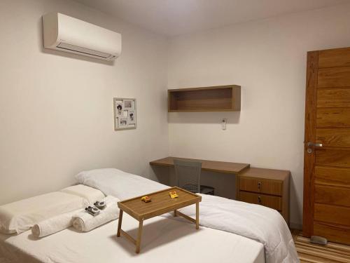 a bedroom with two beds and a desk and a table at Praia de Ipitanga in Lauro de Freitas