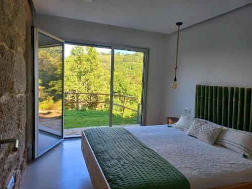 a bedroom with a bed and a large window at Casa de Suelas in Lavradas
