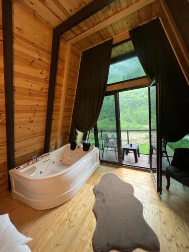 a bath tub in a room with a large window at Çınar suit bungalov in Çamlıhemşin