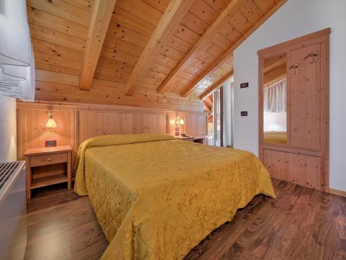 a bedroom with a bed in a room with wooden ceilings at Hotel Garni La Vigna in San Michele allʼAdige