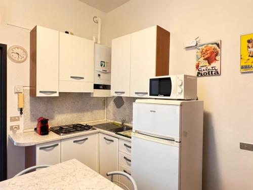 a kitchen with white cabinets and a white refrigerator at Appartamenti I Liutai in Cremona