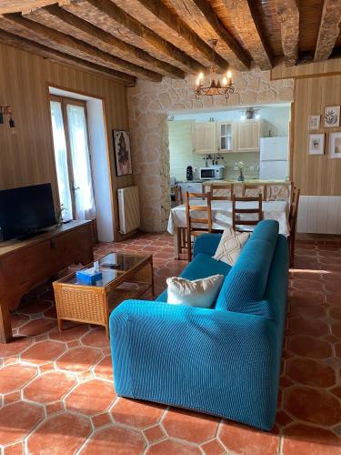 un salon avec un canapé bleu et une cuisine dans l'établissement Gîte du Prieuré de Corbrandes - Longère typique en pleine nature - Entre Chambord et Beauval, 6 pers, animaux OK, à Soings-en-Sologne